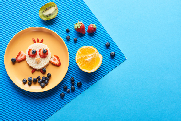 pohled shora na desku s ozdobnou zvířecí barvou z potravin na modrém pozadí - Fotografie, Obrázek