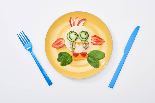 top view of plate with fancy cow made of food for childrens breakfast near cutlery on white background - Photo, Image