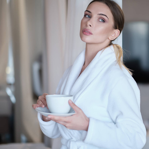 girl in a bathrobe drinks morning coffee - Φωτογραφία, εικόνα