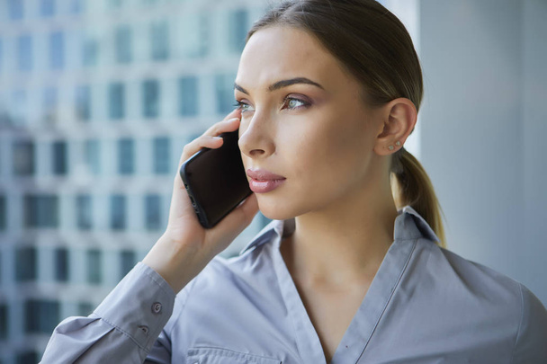 Beautiful business woman with smartphone on the background of th - Foto, Bild