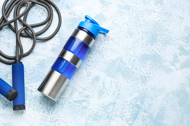 Sport vizes palackot és ugró kötél színes háttér - Fotó, kép