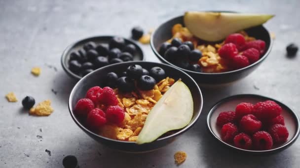 Flocons de maïs dorés aux fruits frais de framboises, bleuets et poires dans un bol en céramique - Séquence, vidéo