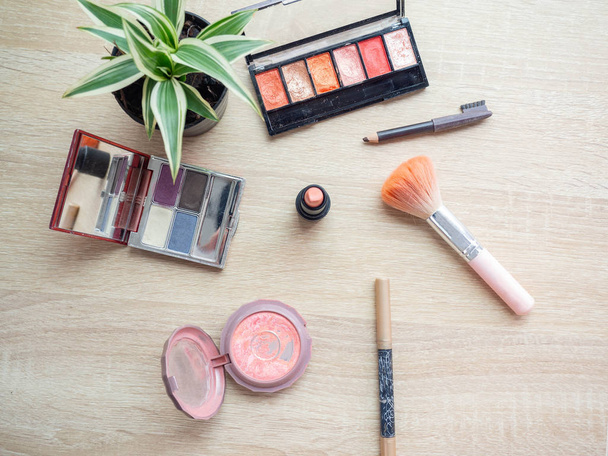 Makeup products with cosmetic bag,Background on top wood table,lip,Powder puff,eyeliner,small tree,Blush on,Shine Light,Makeup mirror - Foto, imagen