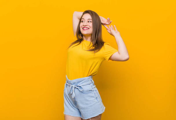 Fiatal nő tinédzser visel sárga inget nyújtó karok, nyugodt helyzetben. - Fotó, kép