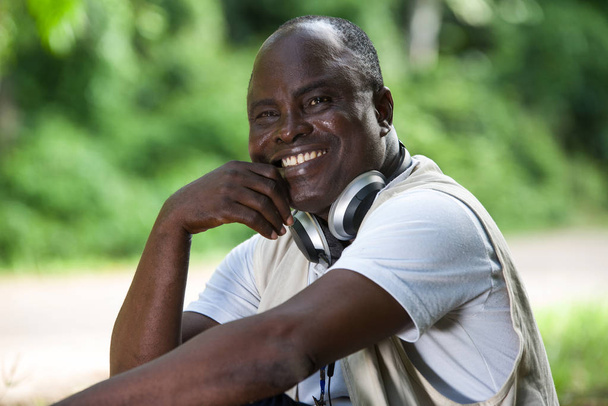 Gros plan d'un homme souriant et exprimant son bonheur assis dans un parc et écoutant de la musique
. - Photo, image