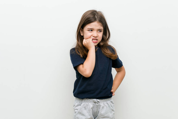 Cute little caucasian girl biting fingernails, nervous and very anxious. - Photo, Image