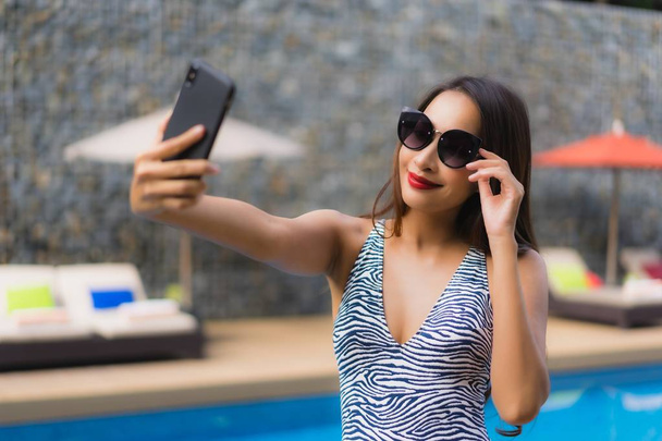 Muotokuva kaunis aasialainen nainen käyttää matkapuhelinta ympärillä ulkona
 - Valokuva, kuva