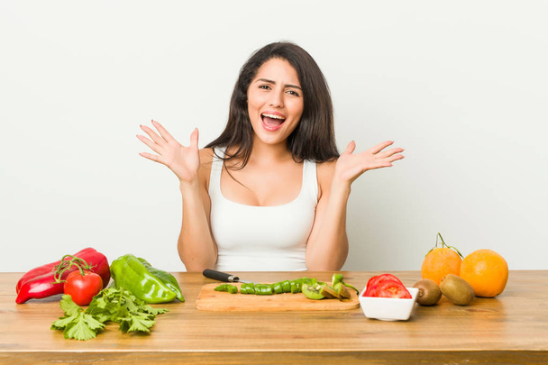 Young curvy woman preparing a healthy meal celebrating a victory or success, he is surprised and shocked. - Photo, Image