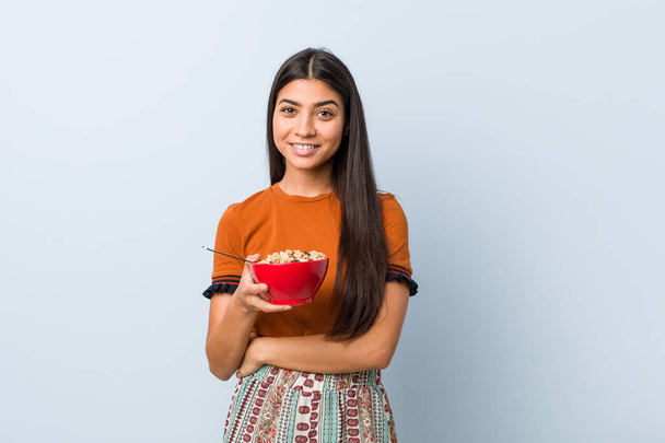Young arab woman holding a cereal bowl smiling confident with crossed arms. - Foto, Bild