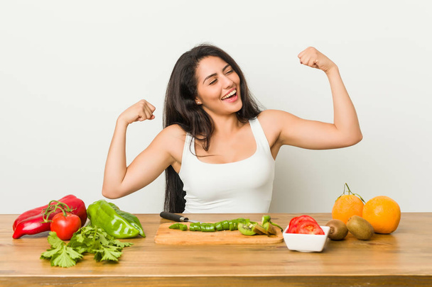 Young curvy woman preparing a healthy meal raising fist after a victory, winner concept. - Photo, Image