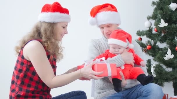 Vacances en famille et concept de Noël. Jeune père et mère avec un enfant déballer un cadeau de Noël
 - Séquence, vidéo