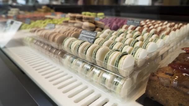 Sortiment barevných tradičních francouzských macaronů ležících v řadách na tržišti, pojetí potravin. Akce. Barevné dorty na pultu obchodu, sladké bonbóny na bázi meringue, zblízka. - Záběry, video