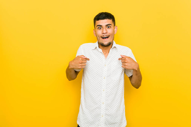 Young hispanic man surprised pointing with finger, smiling broadly. - Fotoğraf, Görsel