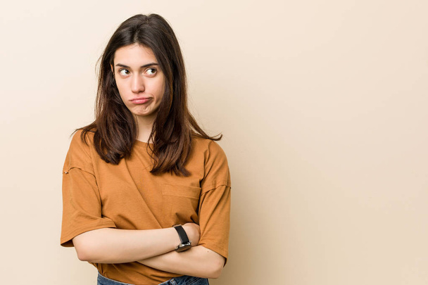 Young brunette woman against a beige background unhappy looking in camera with sarcastic expression. - Foto, Imagem
