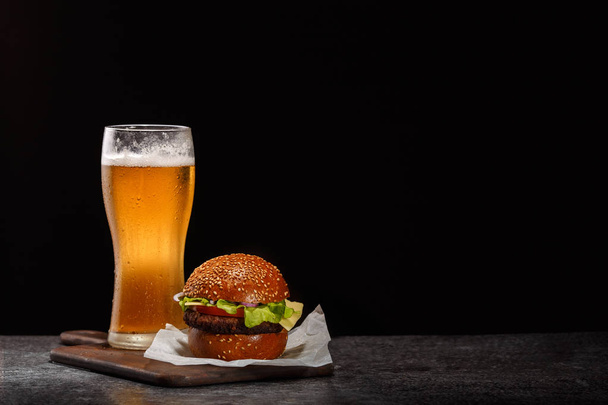 Frosty glass of light beer with hamburger - 写真・画像