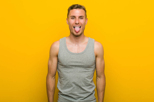 Young caucasian sport man funny and friendly sticking out tongue. - Foto, Bild
