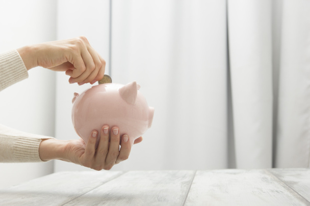 γυναίκα χέρι βάζοντας χρήματα νόμισμα σε piggy για την εξοικονόμηση πλούτου χρήματα και την οικονομική έννοια - Φωτογραφία, εικόνα