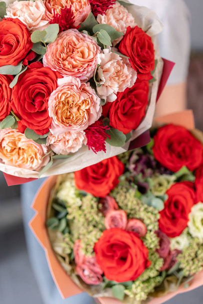 zwei schöne Sträuße gemischter Blumen in Frauenhänden. die Arbeit des Blumenhändlers in einem Blumenladen. frische Schnittblume. rote und rosa Farbe - Foto, Bild