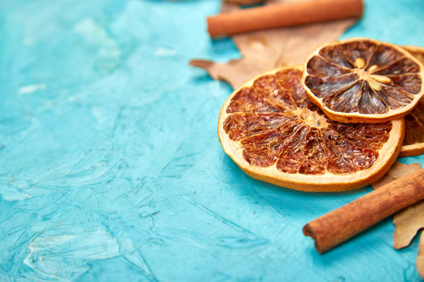 Autumn composition background with slices of dried oranges, leaves and cinnamon on a blue background, autumn concept, flat lay, top view - Photo, Image