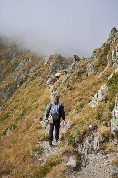 Man with backpack hiking on a mountain trail - Valokuva, kuva