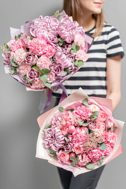 Twee prachtige boeketten van gemengde bloemen in dames handen. het werk van de bloemist in een bloemenwinkel. Delicate pastel kleur. Verse snijbloem. Roze kleur - Foto, afbeelding