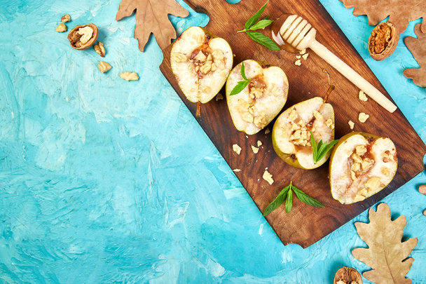 Tasty roast pears with honey and walnuts on wooden board on blue background table. Top view.  Flat lay. Copy space. - Φωτογραφία, εικόνα