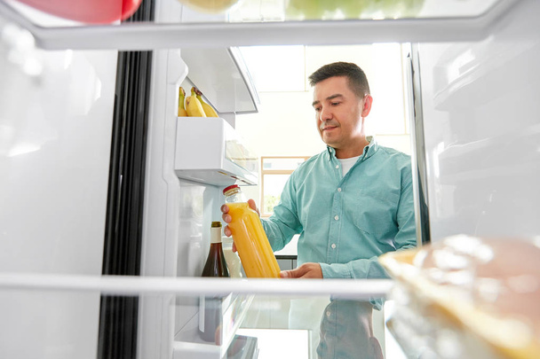 man taking juice from fridge at home kitchen - Foto, Imagen