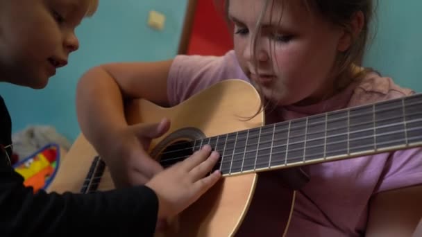 As crianças aprendem a tocar guitarra. Close-up de uma guitarra e cordas com as mãos das crianças
. - Filmagem, Vídeo