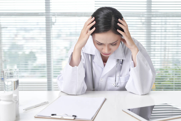 Doctor has a headache sitting at the desk. - Photo, Image