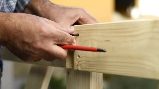 Artisanat charpentier adulte avec tournevis visser la vis pour fixer les planches d'une clôture en bois. Fais-le toi-même. Images au ralenti
. - Séquence, vidéo