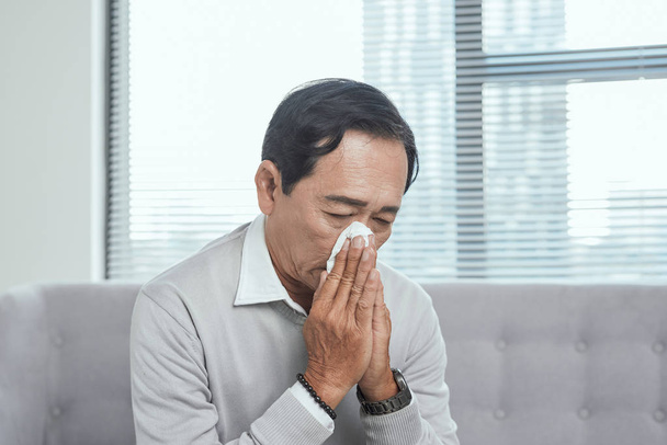 Asiático anciano anciano enfermarse limpiar la nariz mocos de la gripe y secreción nasal cuando el cambio de estación
 - Foto, imagen