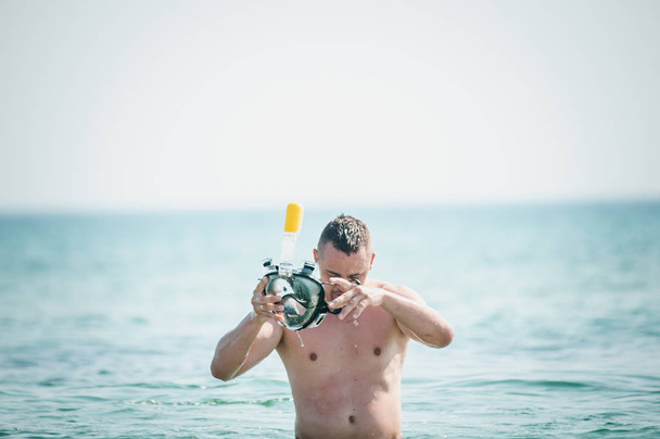 Mann mit Schwimmmaske in der Hand geht aufs Wasser - Foto, Bild