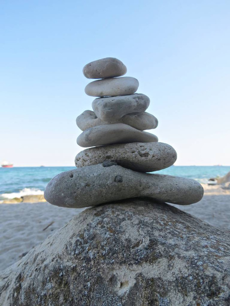 Strand kő Zen Cairn. Egy kőpiramis a tenger partján. Egyszerű nyugalom kavicsok verem, rock Zen szobor, egy kő torony. - Fotó, kép