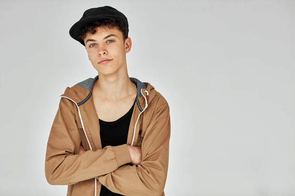 Handsome teen in beige jacket and black cap posing in studio - Fotoğraf, Görsel