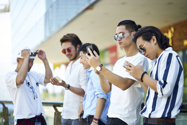 Nuoret aasialaiset aikuiset miehet hengailla yhdessä
 - Valokuva, kuva