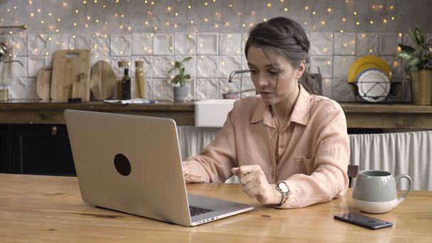 Felnőtt sötét hajú nő dolgozik laptop a konyhában otthon, idő telik a hatása. Stock Footage. A modern technológiák és belső koncepció, női gépelés üzenet. - Fotó, kép