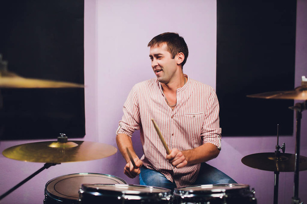 Young man behind drum-type installation in a professional recording studio. - Φωτογραφία, εικόνα