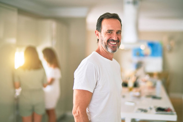 Középkorú jóképű férfi áll a konyhában mosolyogva - Fotó, kép