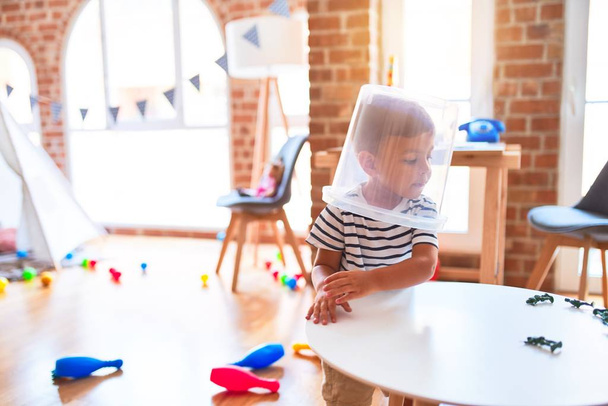 Schöner Kleinkind-Junge spielt im Kindergarten mit Plastikkorb - Foto, Bild