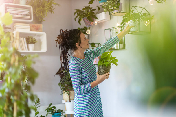 Giovane donna prendersi cura delle sue piante in vaso a casa
 - Foto, immagini