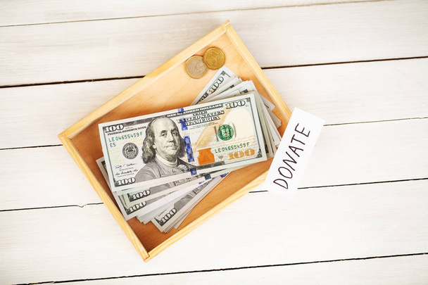 Spenden Sie! Box mit Geld auf weißem Holz Hintergrund - Foto, Bild