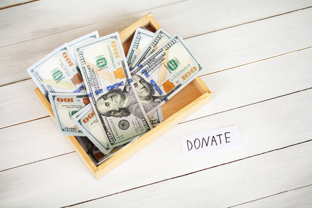 Пожертвовать зачатие. Коробка с деньгами на белом деревянном фоне
 - Фото, изображение
