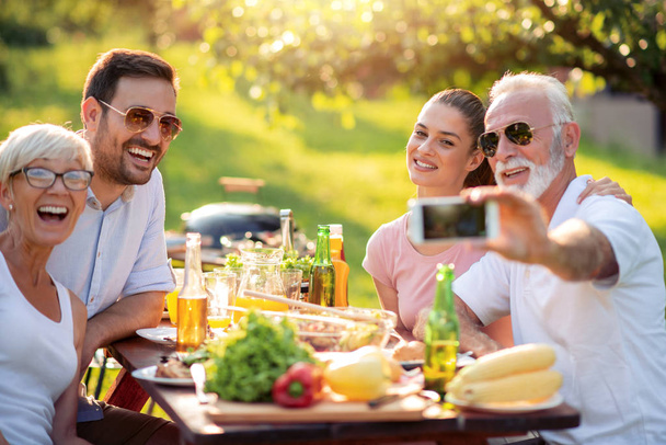 Családi ebédelni a nyári kerti party, hogy selfie. Szabadidő-, élelmiszer-, család-és ünnepnapokon koncepció. - Fotó, kép