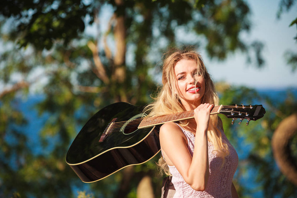 Blonde woman with acoustic guitar on seaside - Фото, изображение