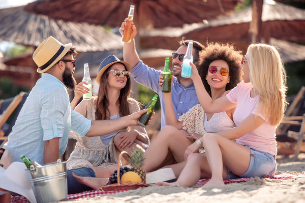 Przyjaciele, zabawy na plaży, popijając zimne piwo. - Zdjęcie, obraz