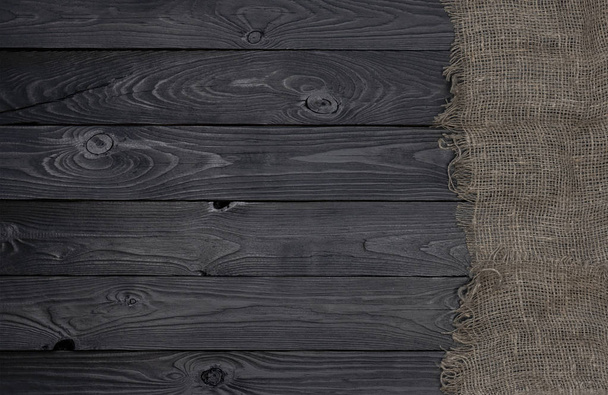 Old burlap fabric napkin on black wooden background, top view - Zdjęcie, obraz
