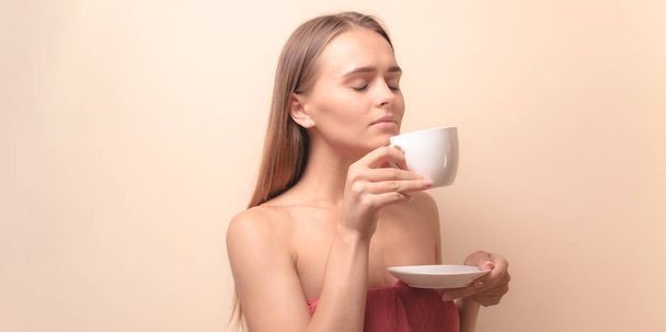 Mujer joven disfrutando de una taza de café. Retrato de mujer con té de la mañana. Copiar espacio
 - Foto, Imagen