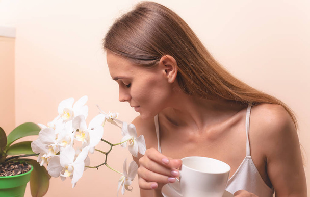 Giovane donna che si gode una tazza di caffè. Ritratto di femmina con tè del mattino. Copia spazio
 - Foto, immagini