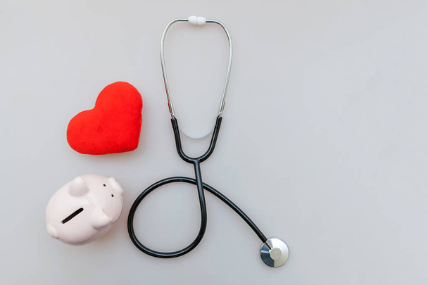 Medicine orvos berendezések sztetoszkóp vagy phonendoszkóp malacka bank és a vörös szív izolált fehér háttér - Fotó, kép