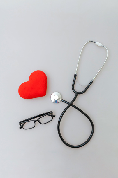 Sprzęt medycyny stetoskop lub okulary fonendoskop i czerwone serce na białym tle. Urządzenie przyrząd do lekarza. Koncepcja ubezpieczenia zdrowotnego na życie - Zdjęcie, obraz